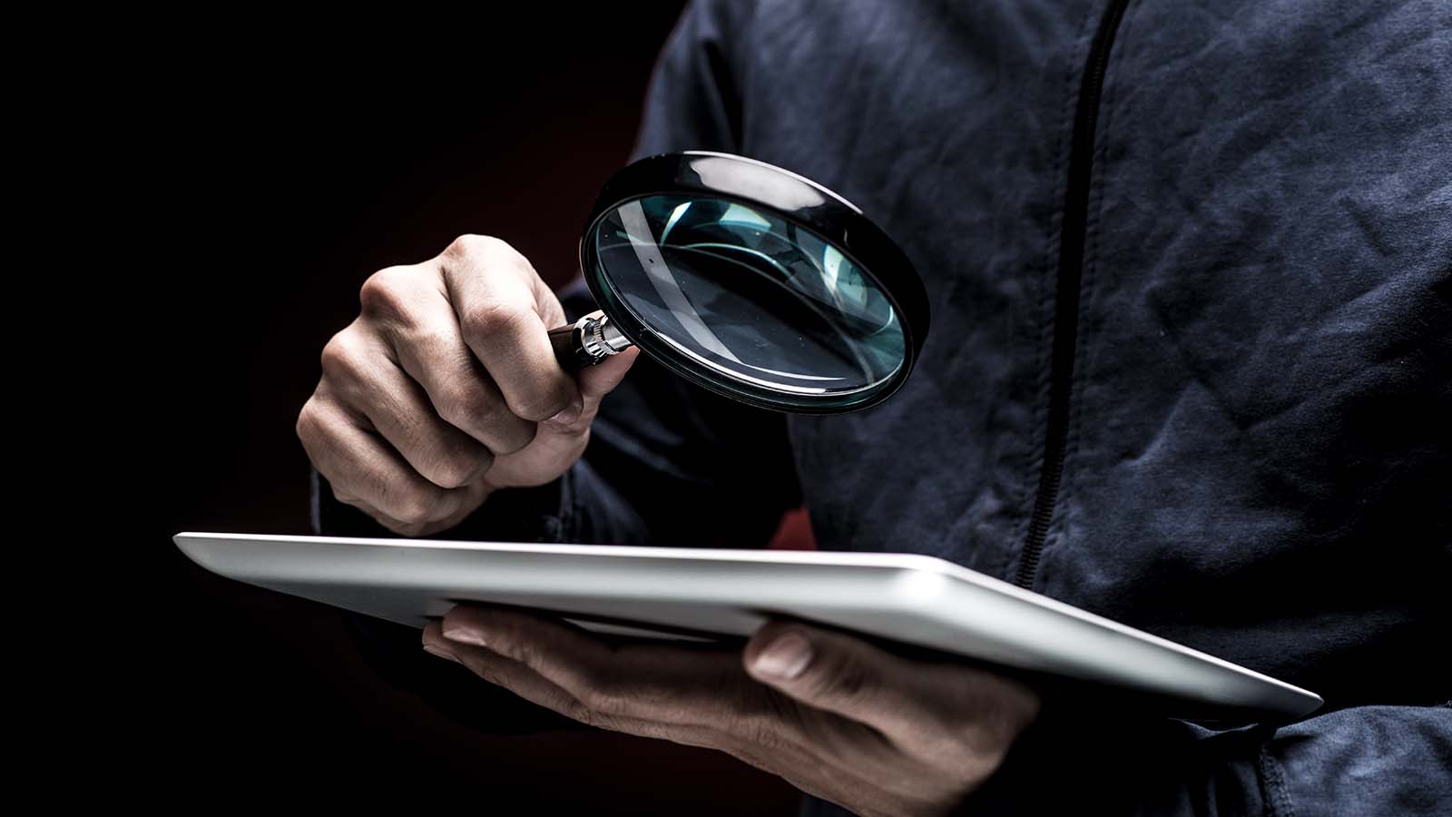 une personne examinant un appareil mobile à l'aide d'une loupe