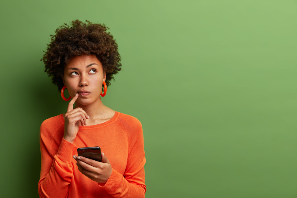 Une femme en pleine réflexion avec son téléphone mobile