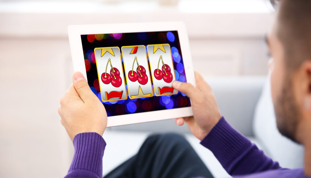 Un homme s'adonne au jeu sur une machine à sous digitale à l'aide d'une tablette.